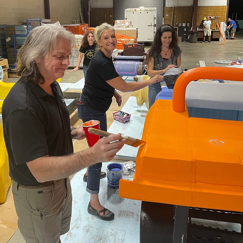 Painting a Blippi Car adaptive costume for children with disabilities that is made from foam.
