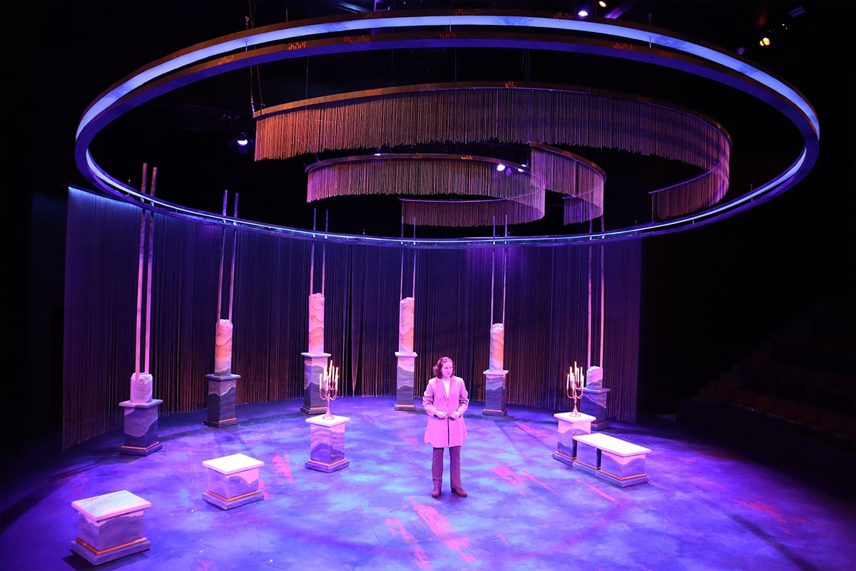 Stage floor and scenery featuring Off Broadway Gold highlights are bathed in purple light.