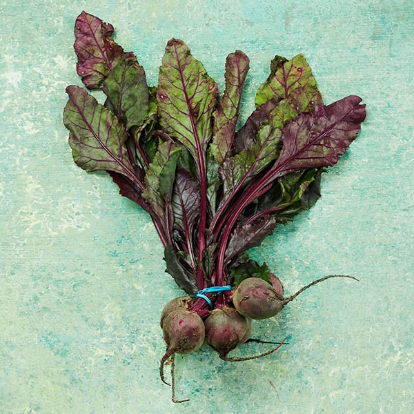 A textured background created with Supersat Paint from Rosco provides the photoshoot backdrop for a bunch of beetroots.